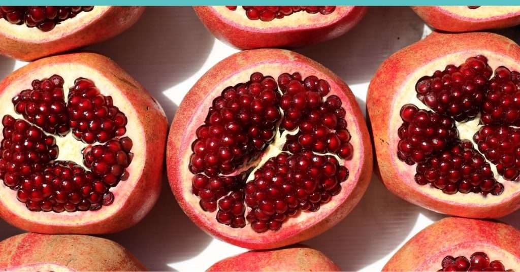 pomegranates that are sliced in half showing the red fruit in the middle