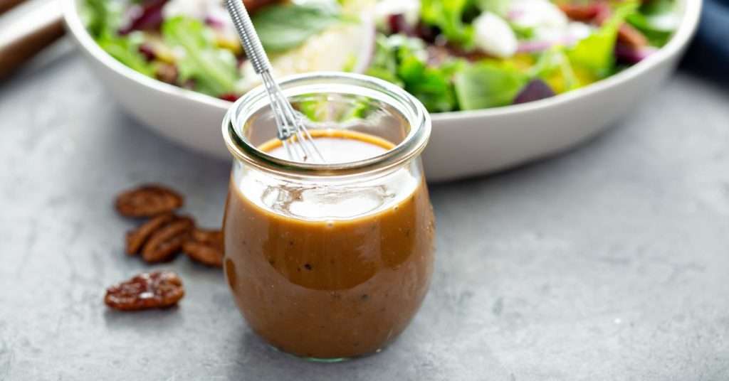 balsamic vinaigrette in a small mason jar with a mixing utensil in it.