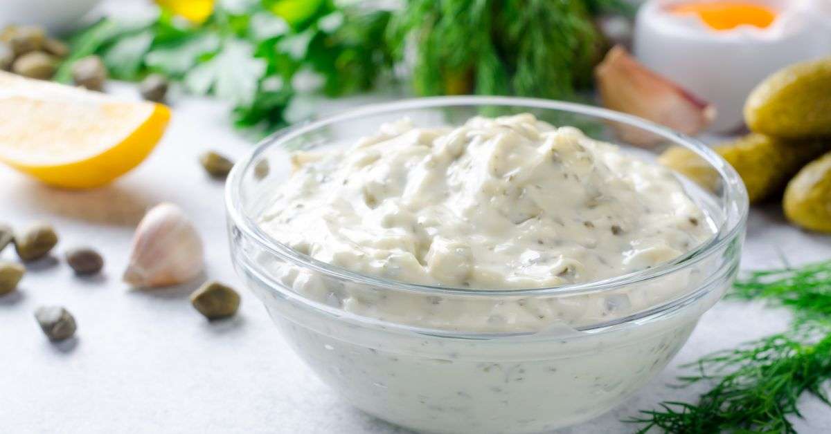 chunky tartar sauce in a glass bowl with some parsley and a lemon in the background.